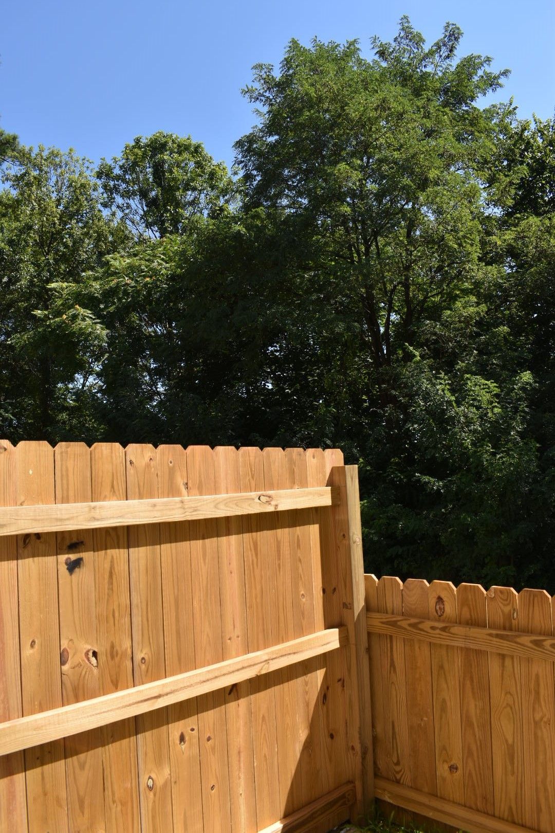 Wooden fence corner with green trees and blue sky in the background