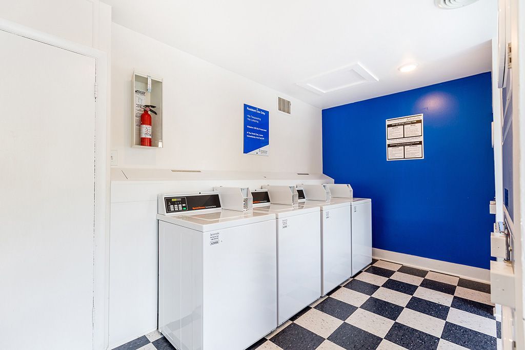 Laundry room with white washers, blue accent wall, and black-and-white checkered floor