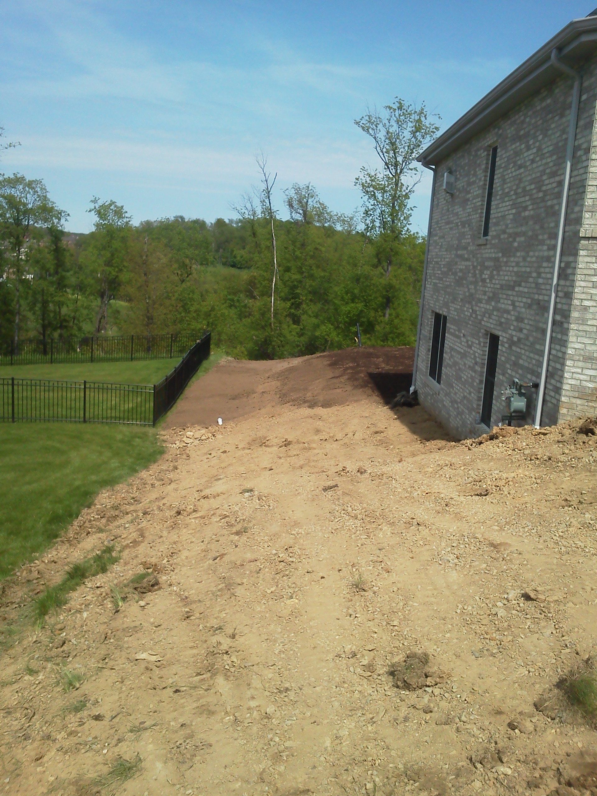 A brick house sits on top of a dirt hill