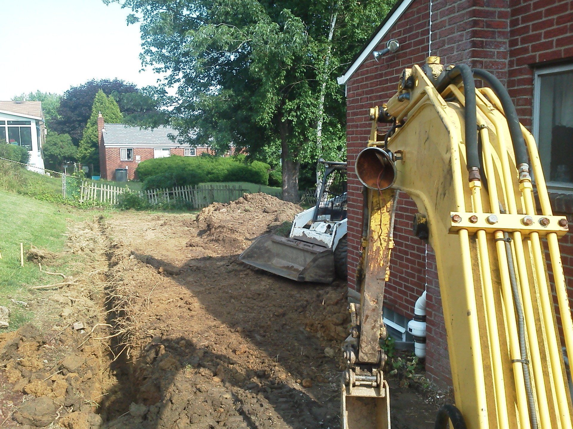 A yellow excavator is sitting in front of a brick building