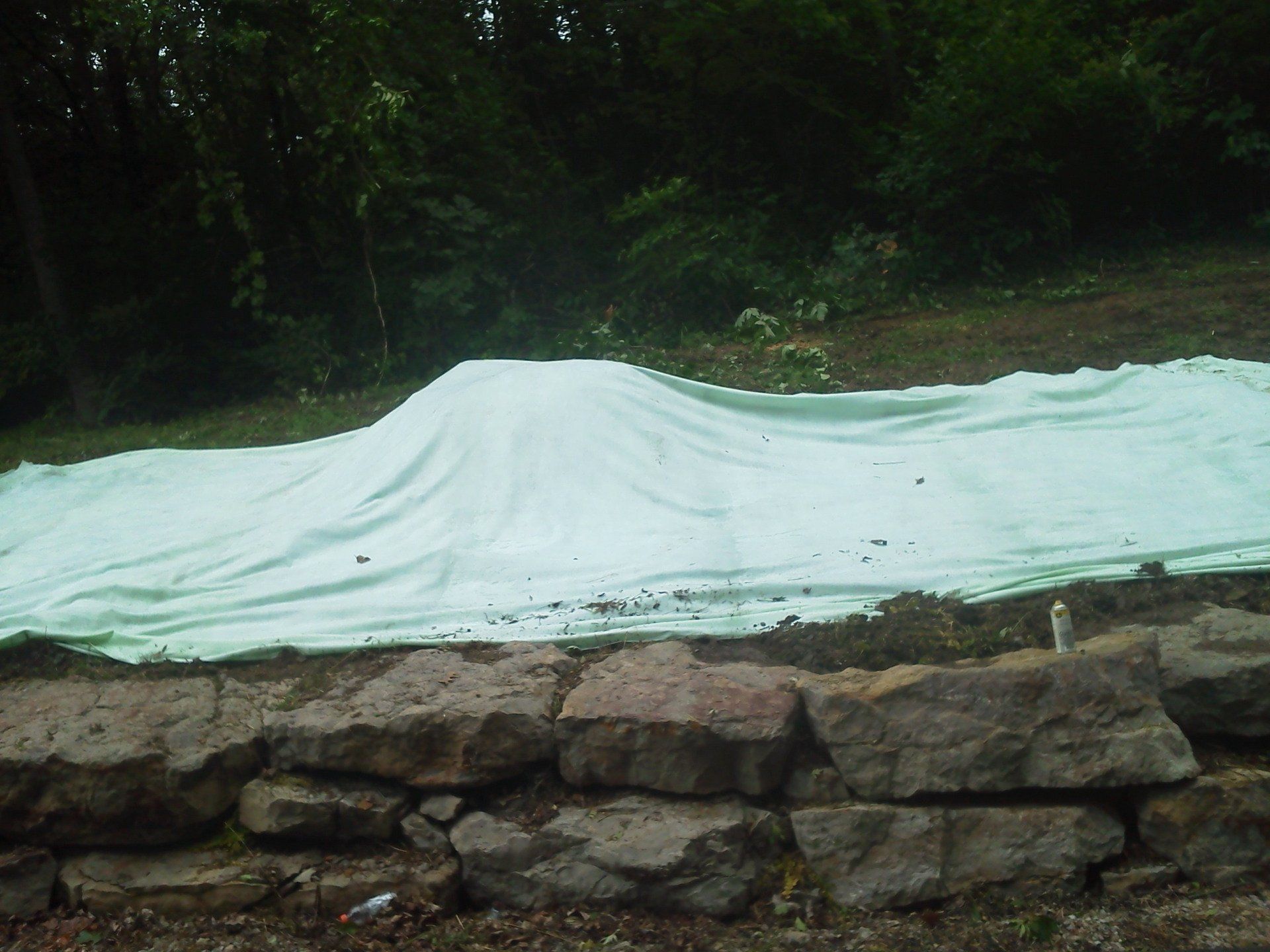A large white tarp is sitting on top of a pile of rocks