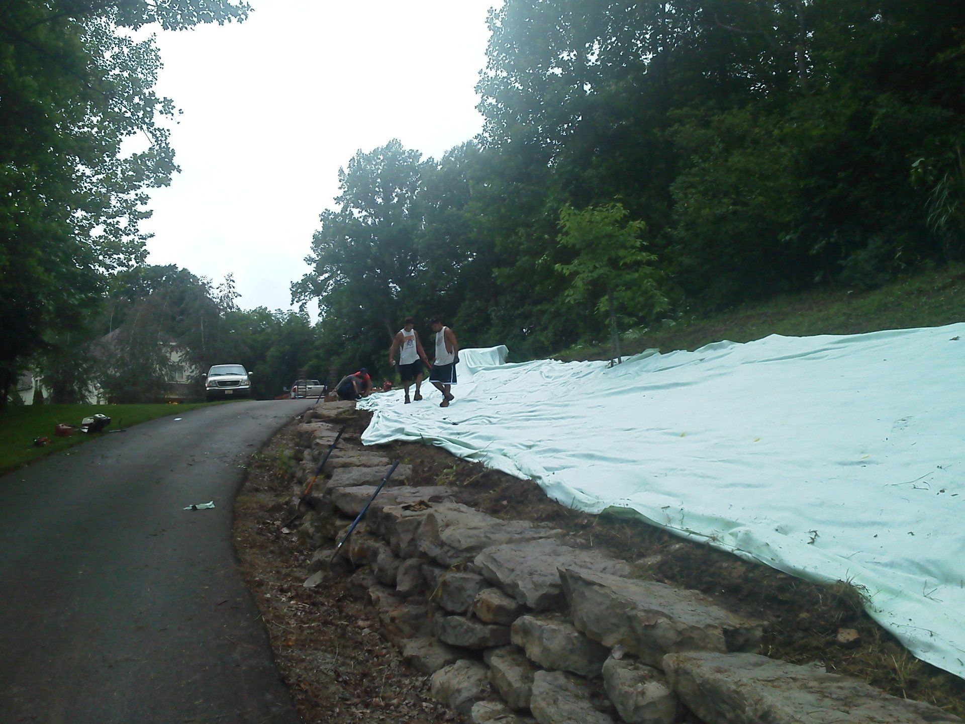 A couple of people walking down a road with trees in the background