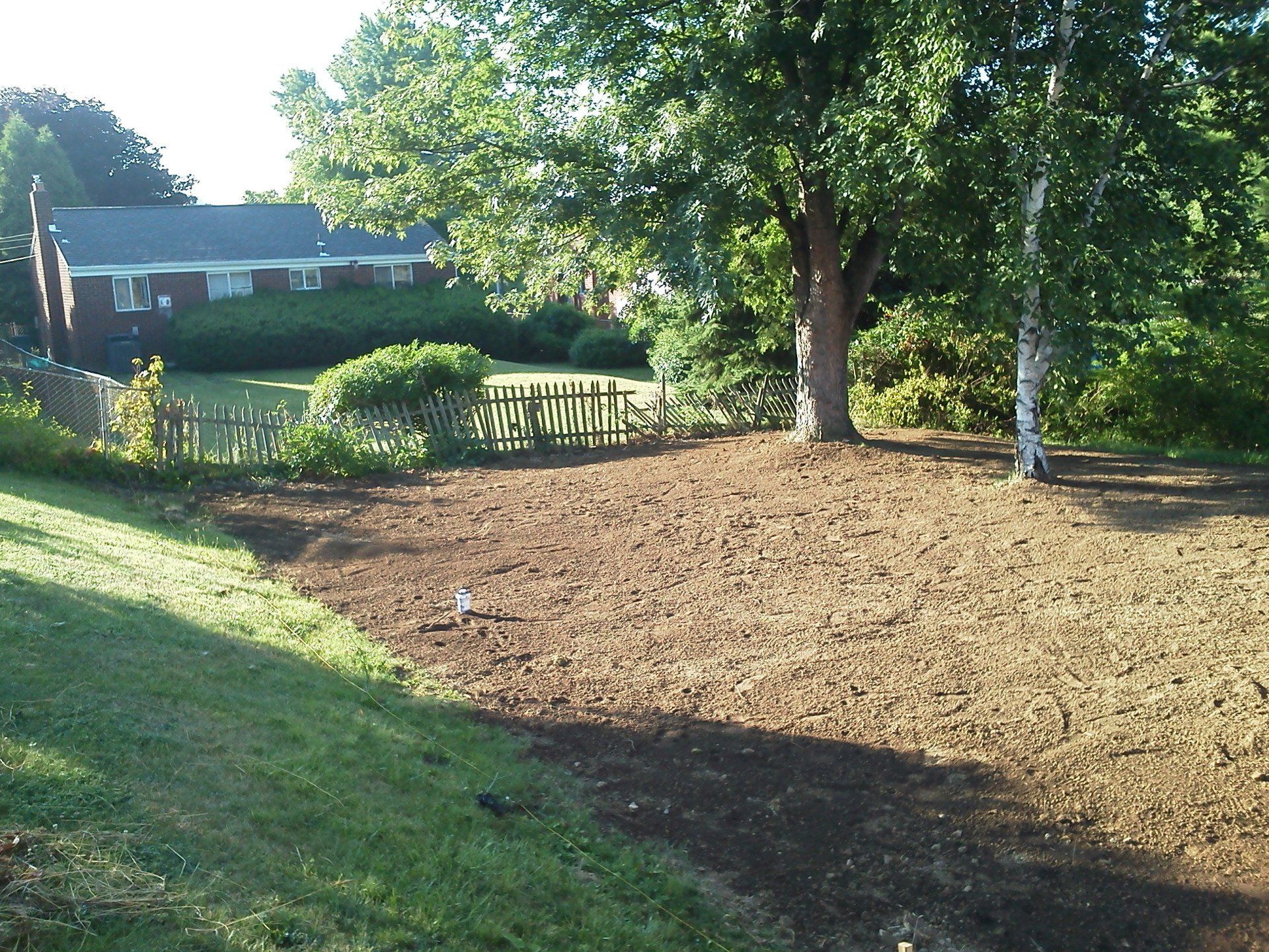 A fenced in yard with trees and a house in the background