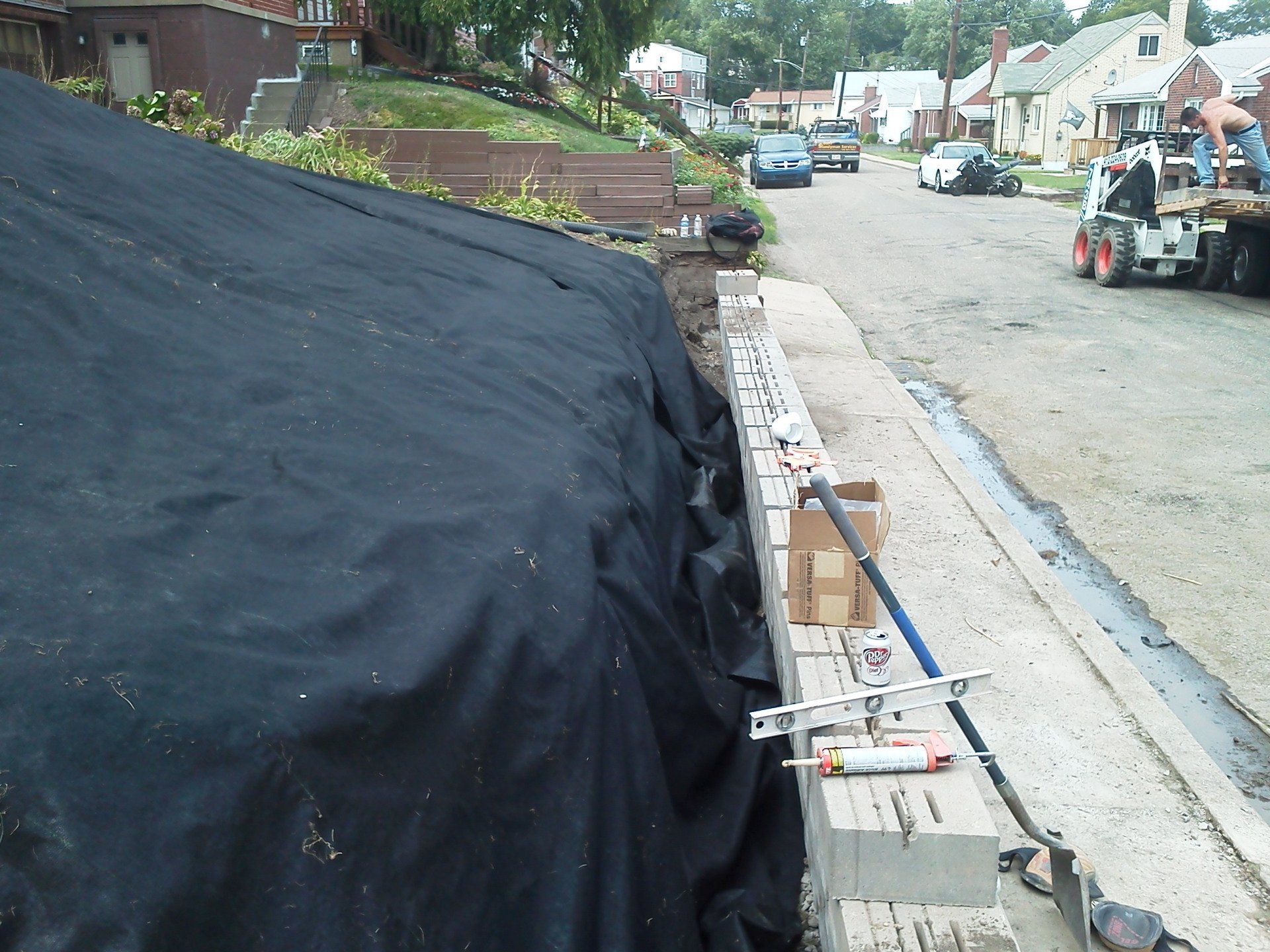 A black tarp is covering a brick wall in a residential area