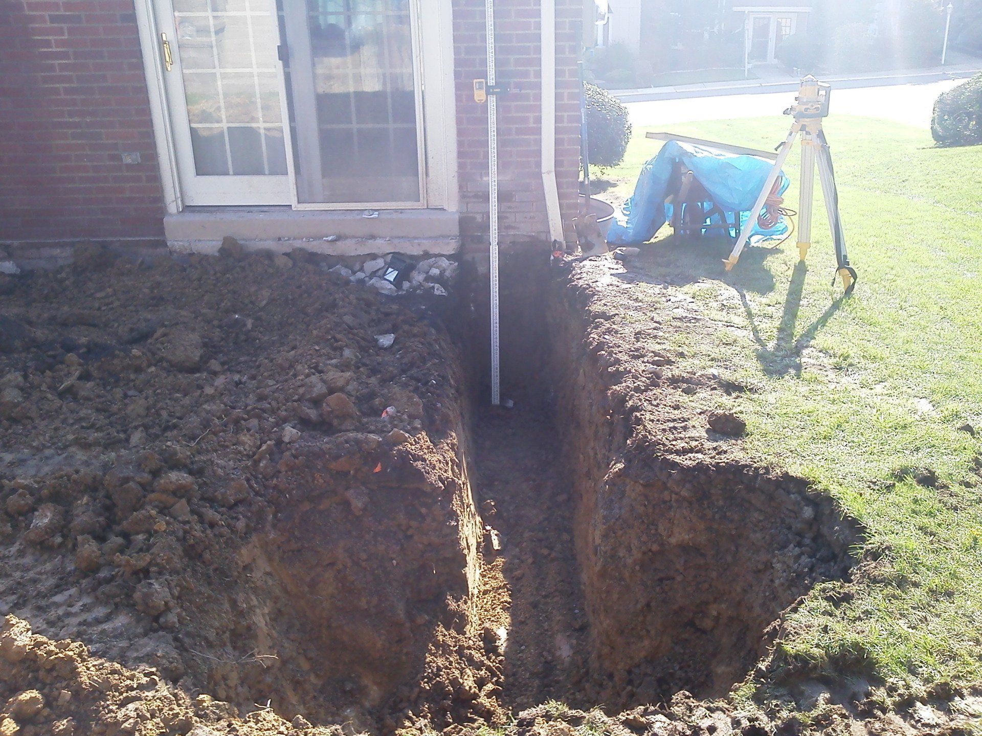 A hole in the ground in front of a brick house