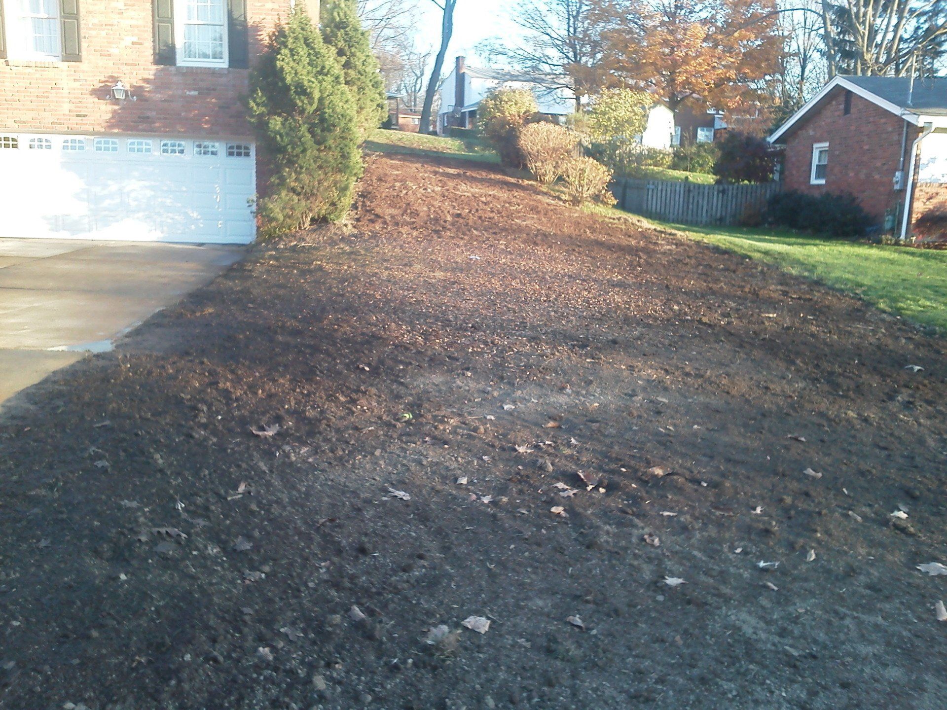 A driveway leading to a brick house with a white garage door
