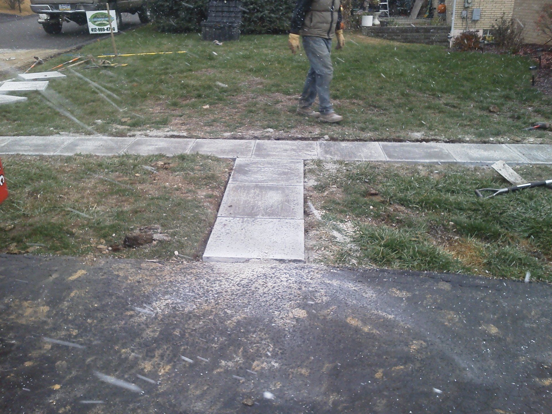 A man is walking down a sidewalk in front of a house.