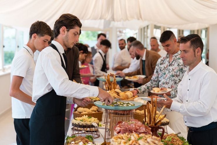 Ospiti che si servono da soli al buffet durante un evento al chiuso con servizio di catering.