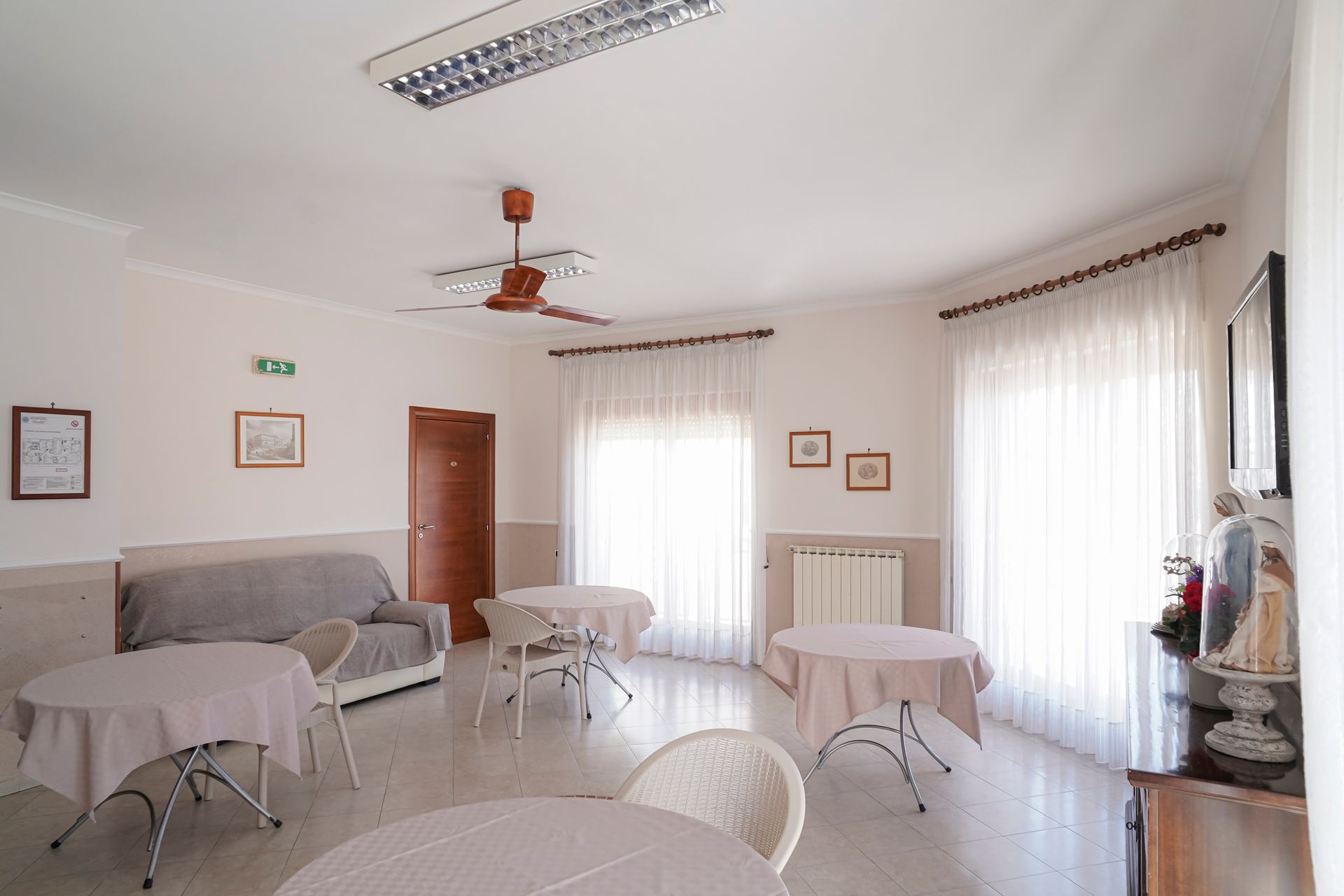 Un soggiorno con tavoli, sedie e ventilatore a soffitto.