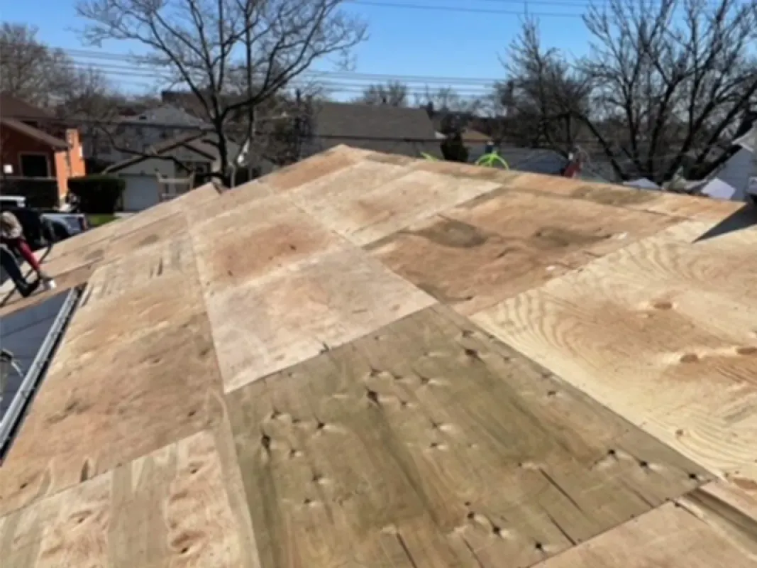 A roof under construction featuring new plywood sheathing panels installed on wooden rafters.