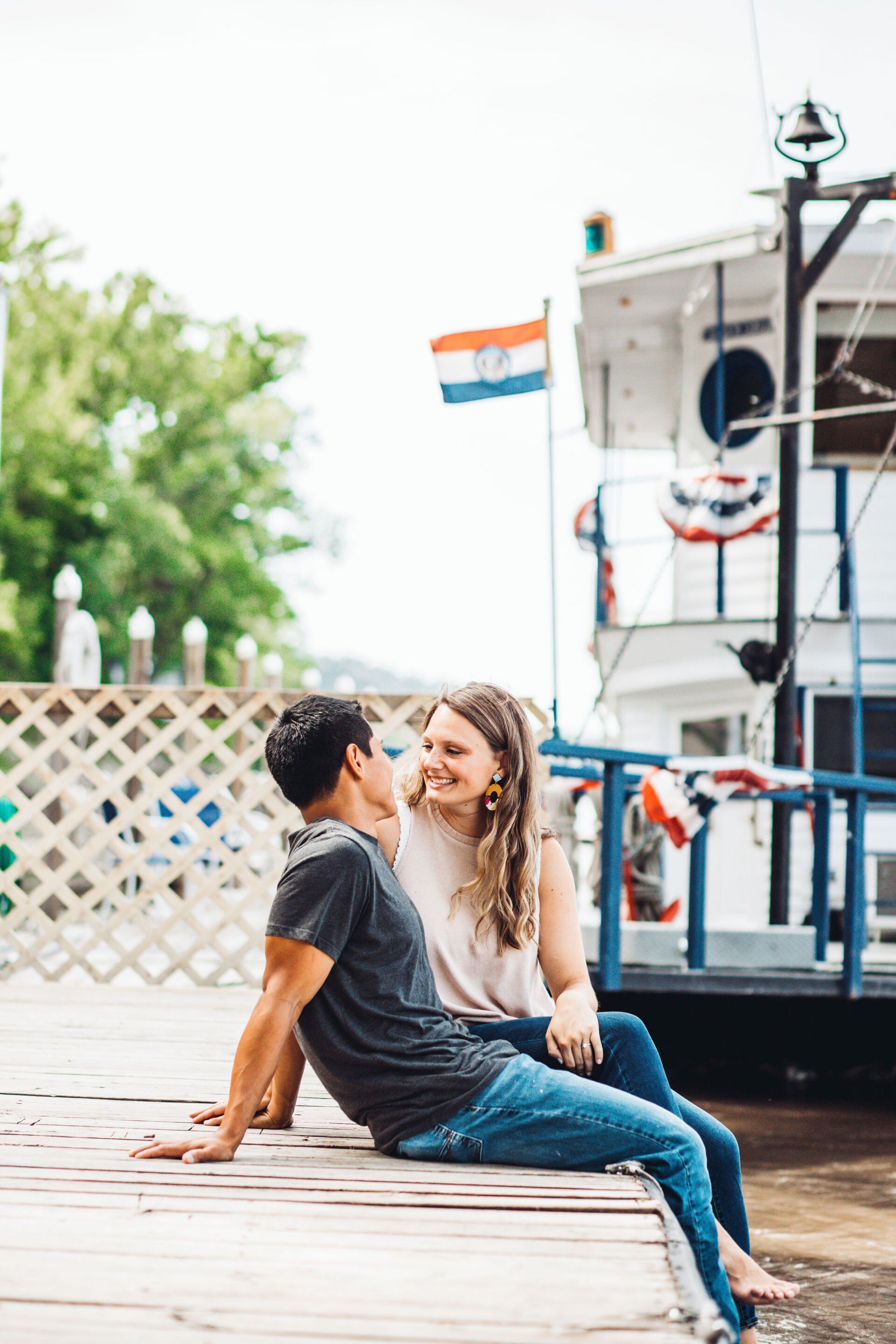 Engaged couple sitting on a dock looking at each other