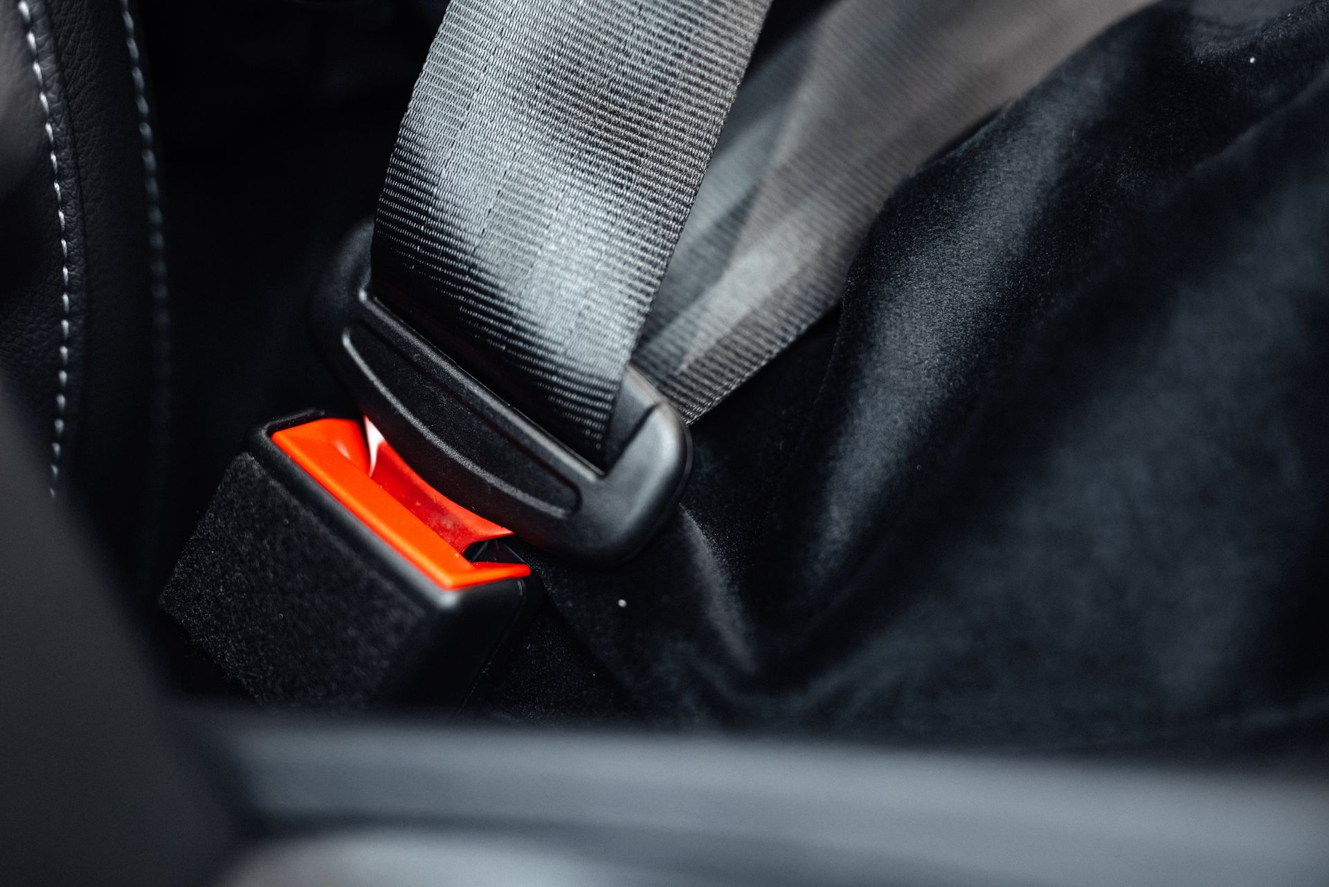 Close-up of a car seat belt buckle with a black strap and red release button Close-up of a car seat belt buckle with a black strap and red release button