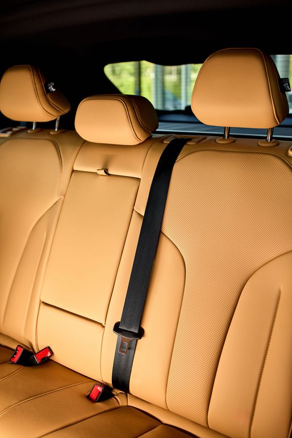 Tan leather car back seat with three headrests and black seat belts Tan leather car back seat with three headrests and black seat belts