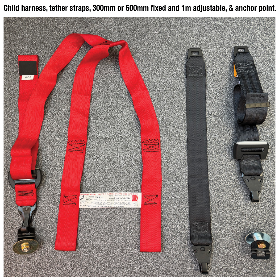 Red child harness and straps with metal buckle, black strap, and anchor point on gray carpet.