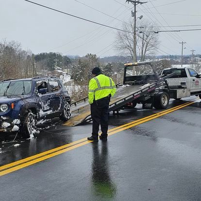 A tow truck is towing a jeep on the side of the road.