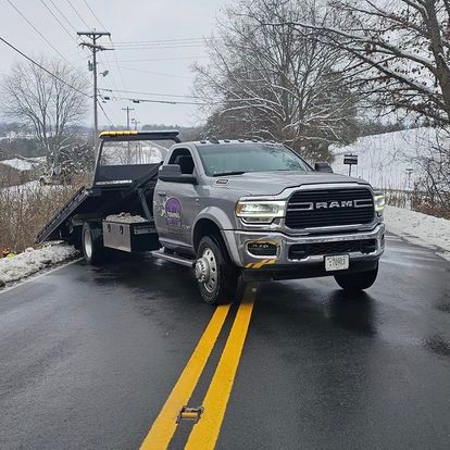 A ram tow truck is driving down a snowy road.