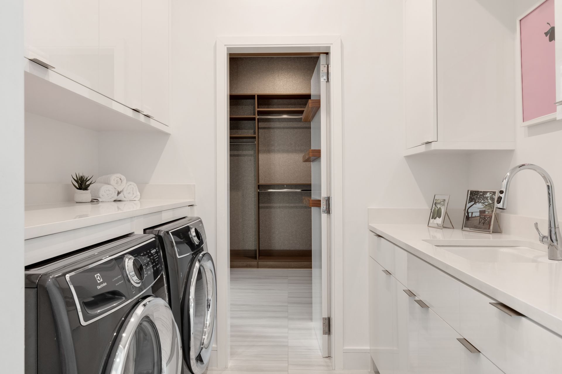 Bright white laundry room with washer, dryer, and open walk-in closet doorway.
