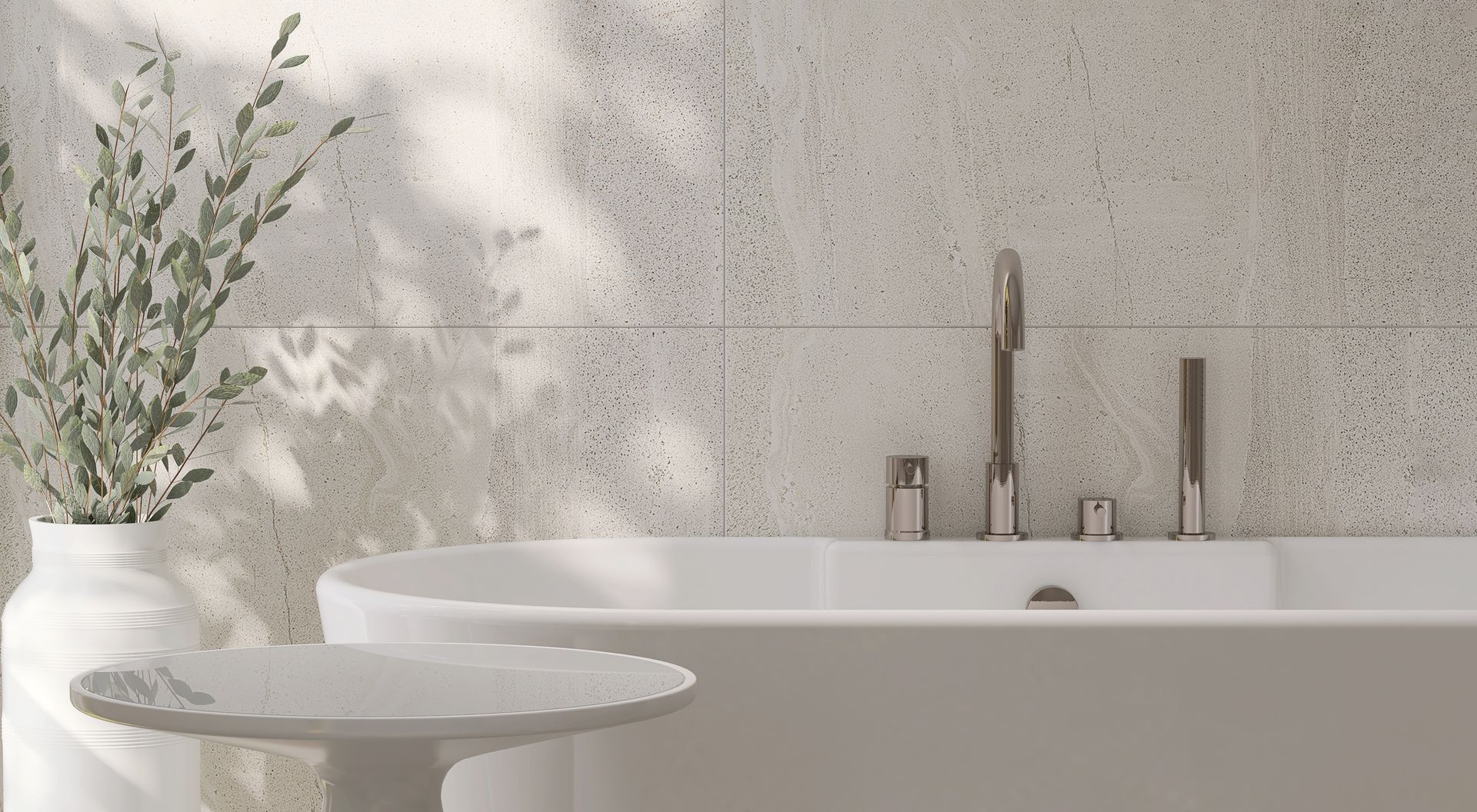 Minimal bathroom with a white tub, wall-mounted sink, and vase of greenery in soft sunlight