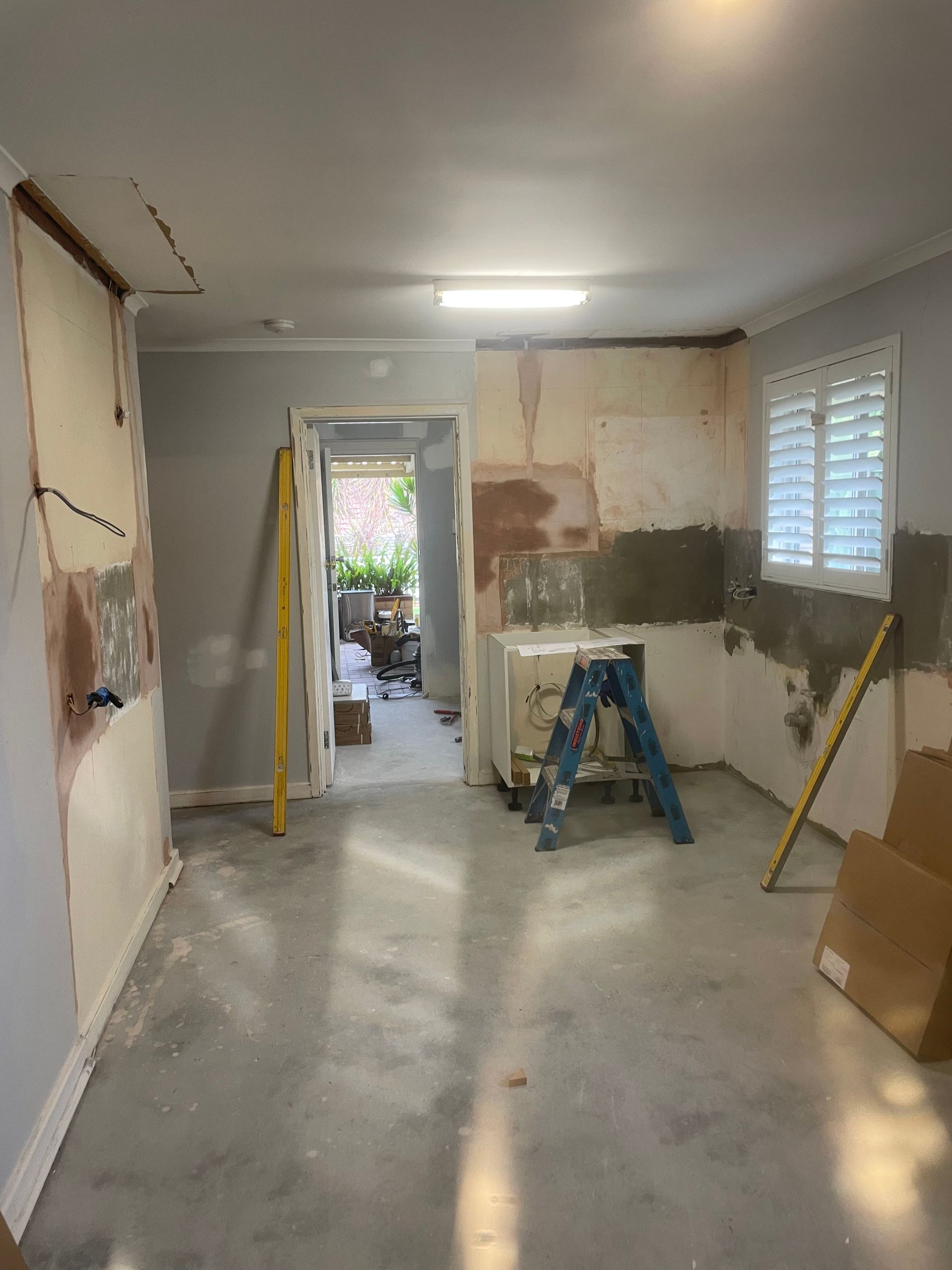 Partially renovated room with patchy walls, stepladder, and tools on the floor