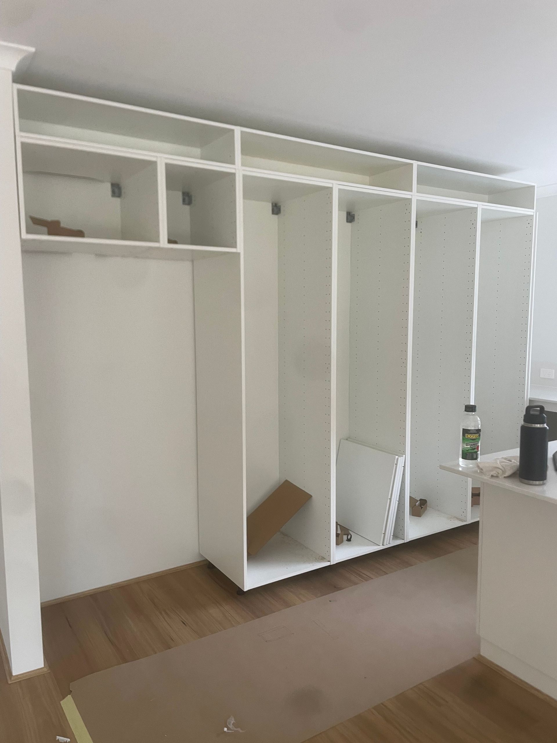 Empty white built-in closet with open doors and shelves in a room with wood floors and a beige rug