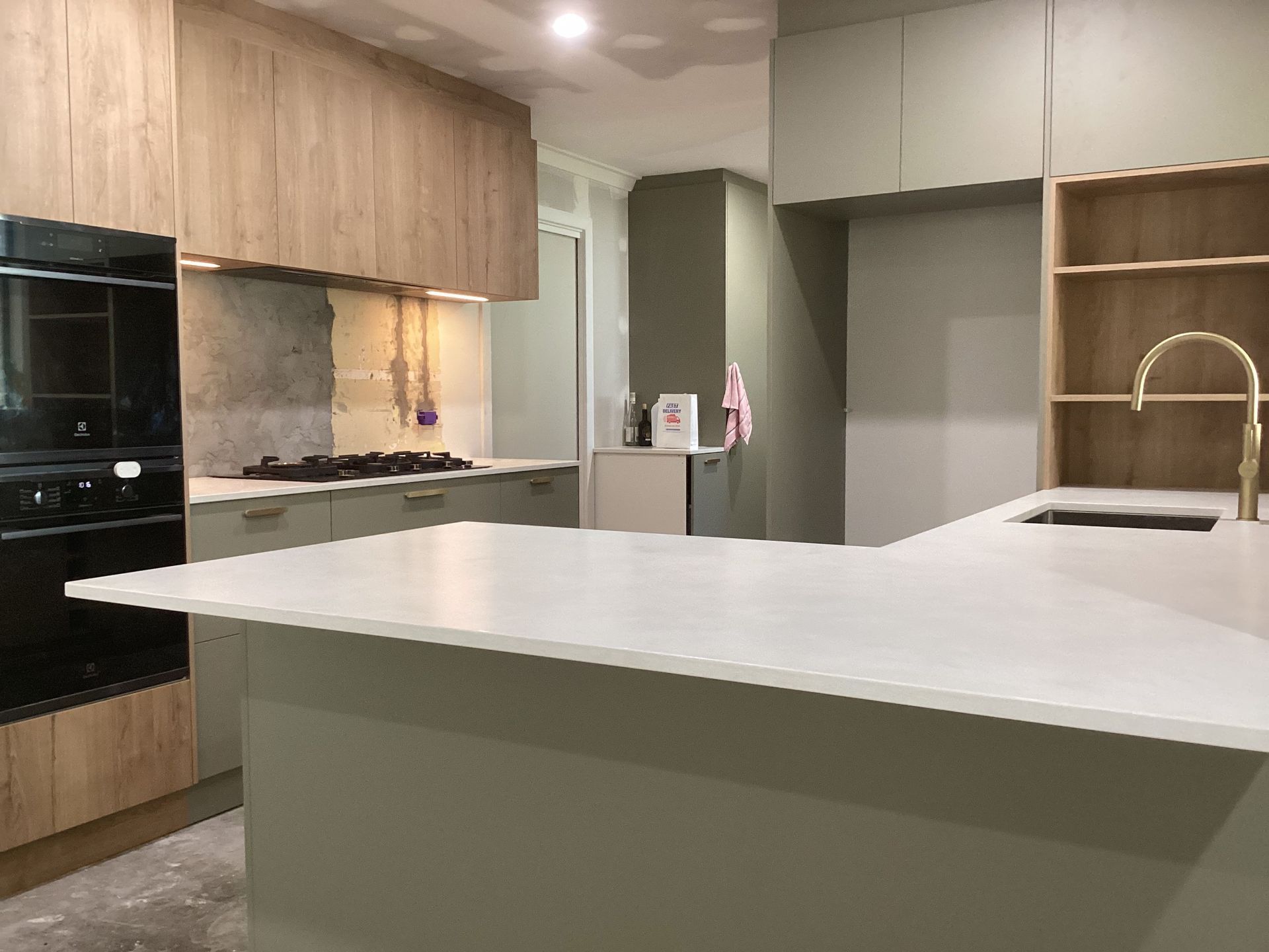 Modern kitchen with a large white island, wood and gray cabinets, and built-in appliances