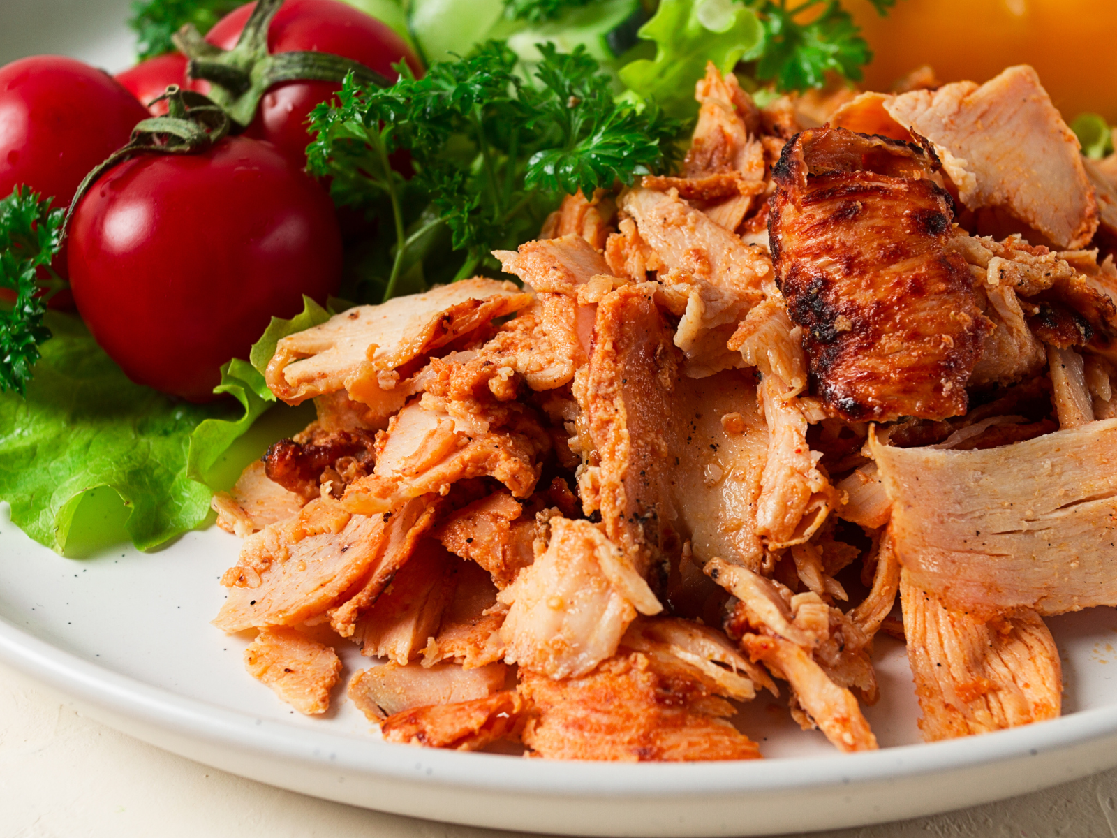 A white plate topped with shredded chicken and vegetables.