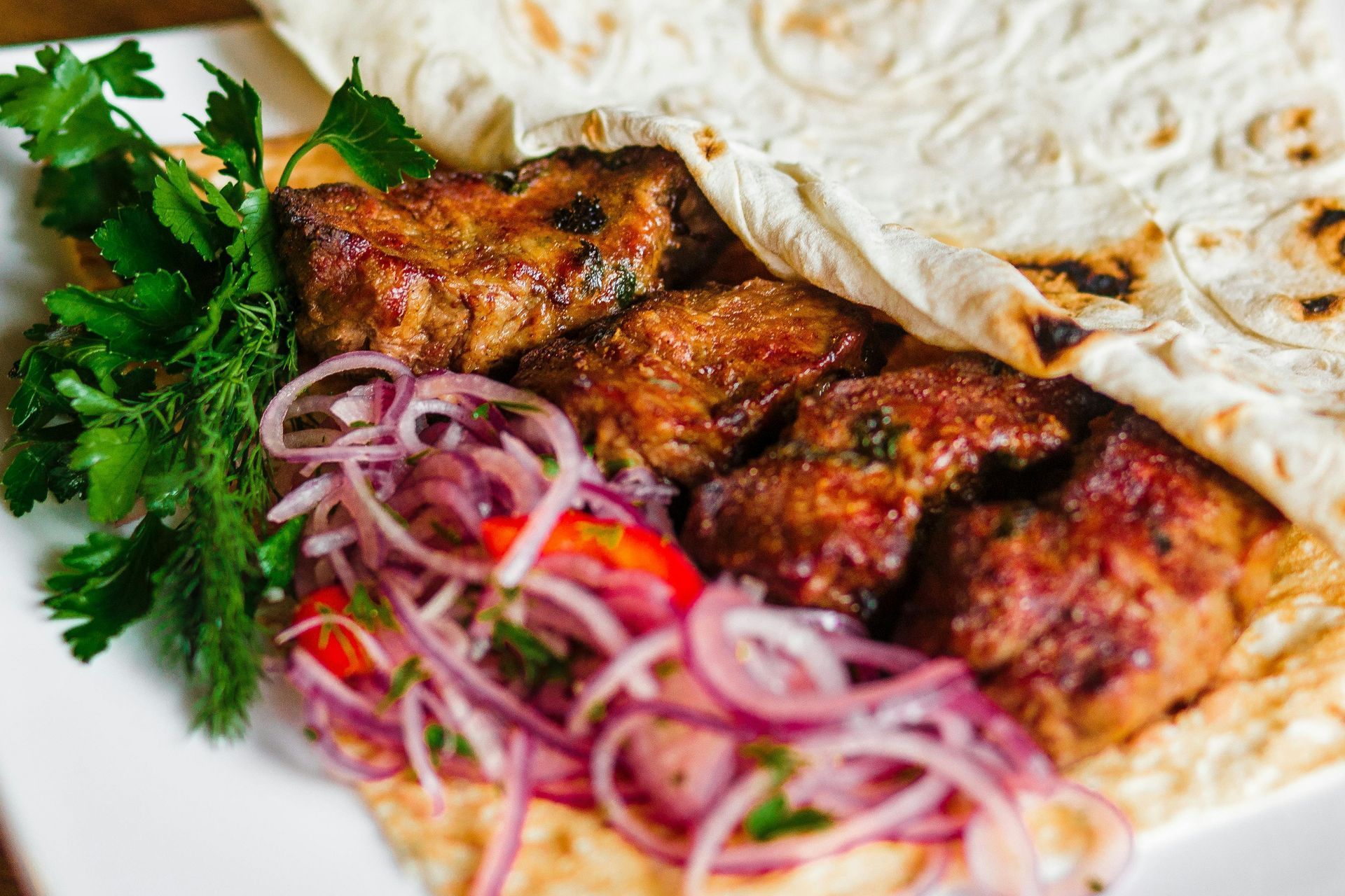 A close up of a plate of food with meat and vegetables on a table.