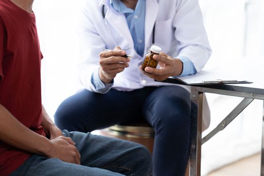 Doctor discussing medication with seated patient in a clinic waiting area