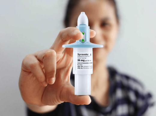 A hand holding a pregnancy test with a positive result, blurred person in the background
