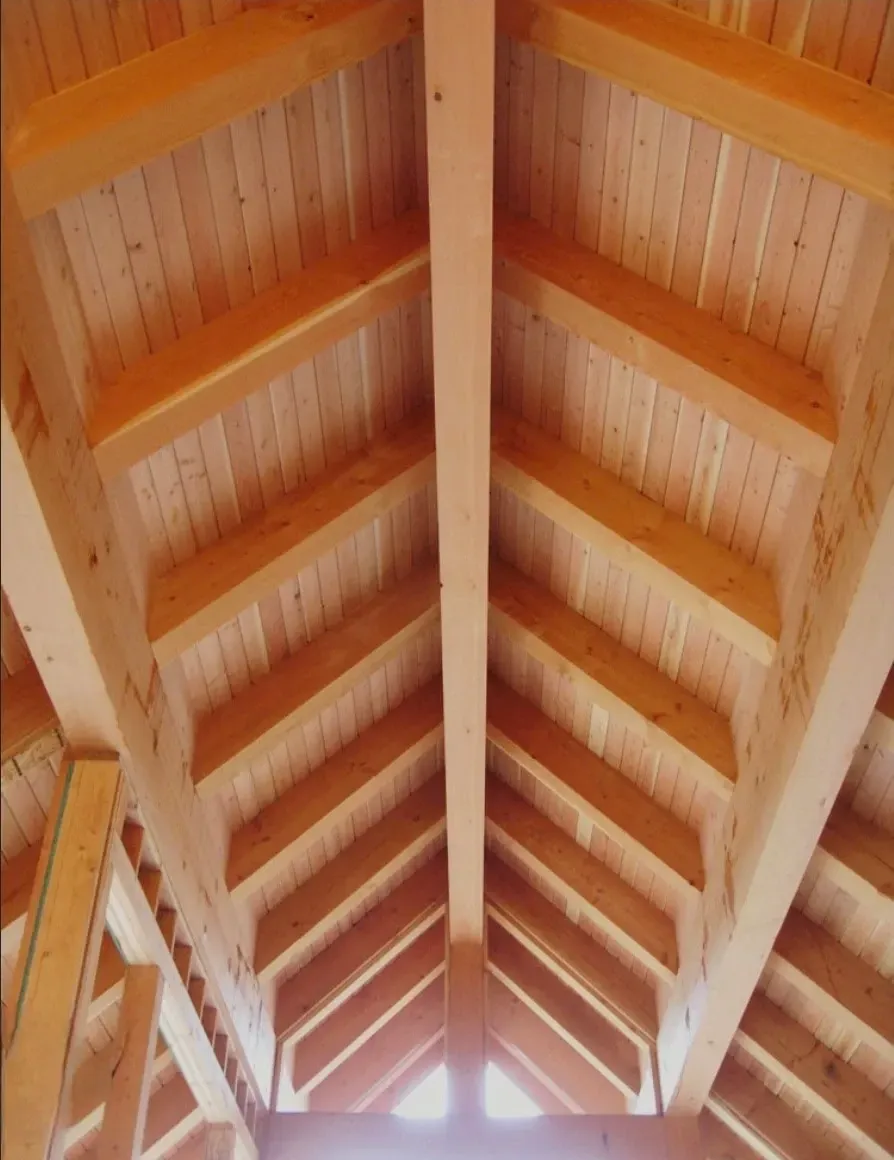 Wooden vaulted ceiling with exposed beams and bright skylight at the peak