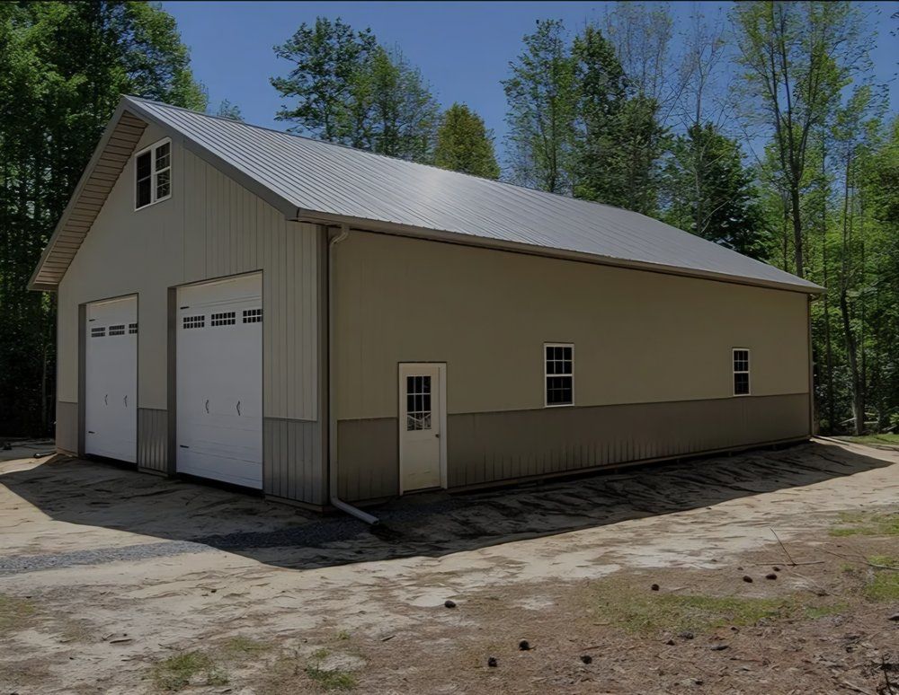 Tan metal garage with two white doors beside a wooded dirt lot