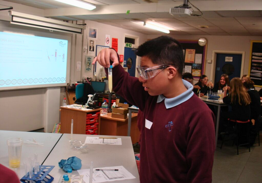 Student holding a test tube in a science classroom lab demonstration