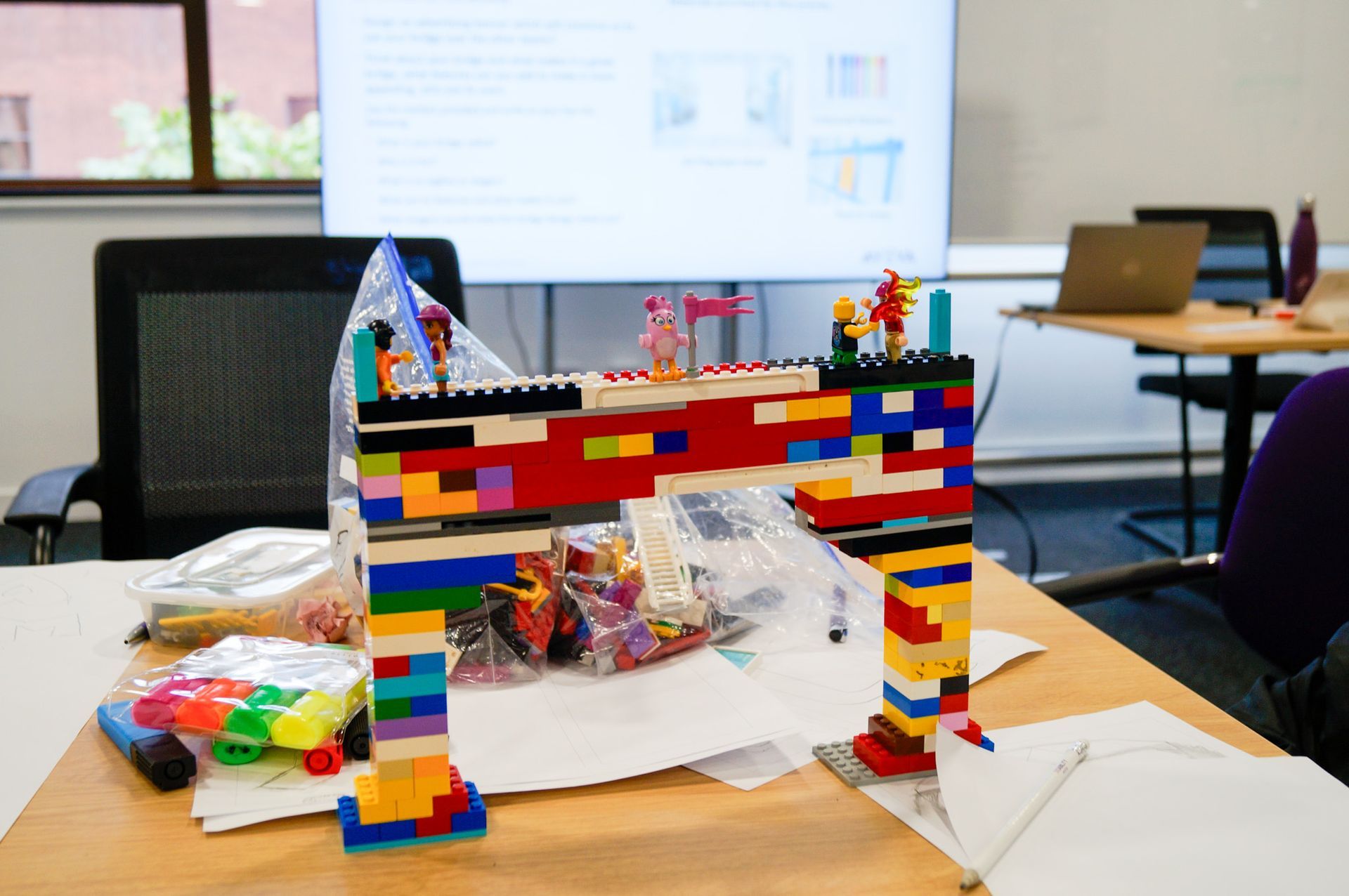 Colorful LEGO bridge model on a table in a classroom or workshop setting