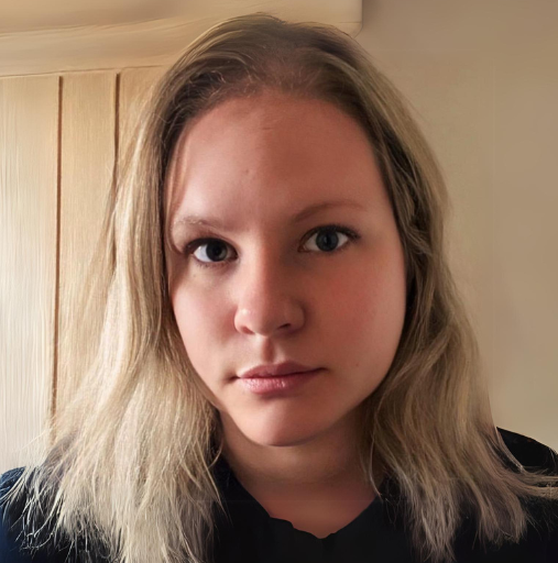 Close-up portrait of a person with light hair in a black shirt, looking at the camera indoors