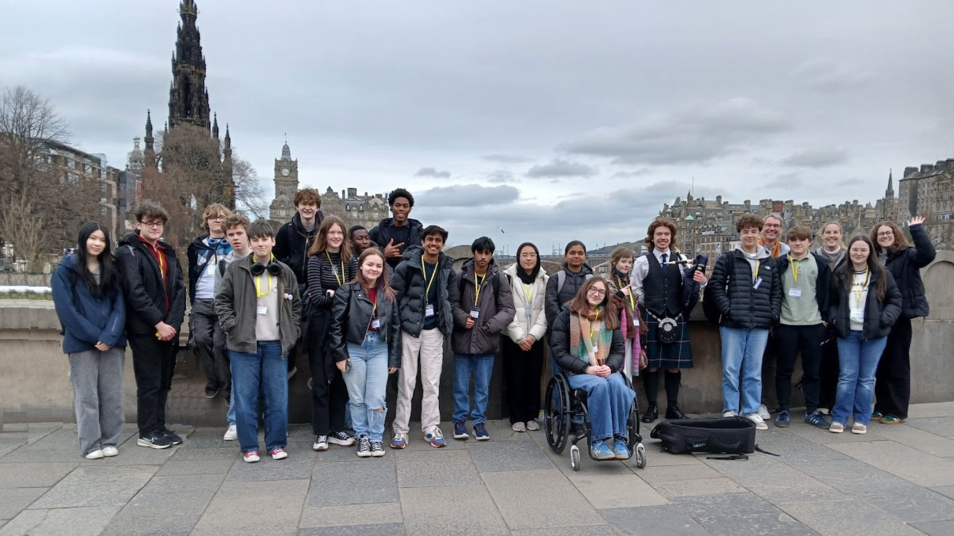 Group of people posing on a cloudy city square with a tall monument in the background