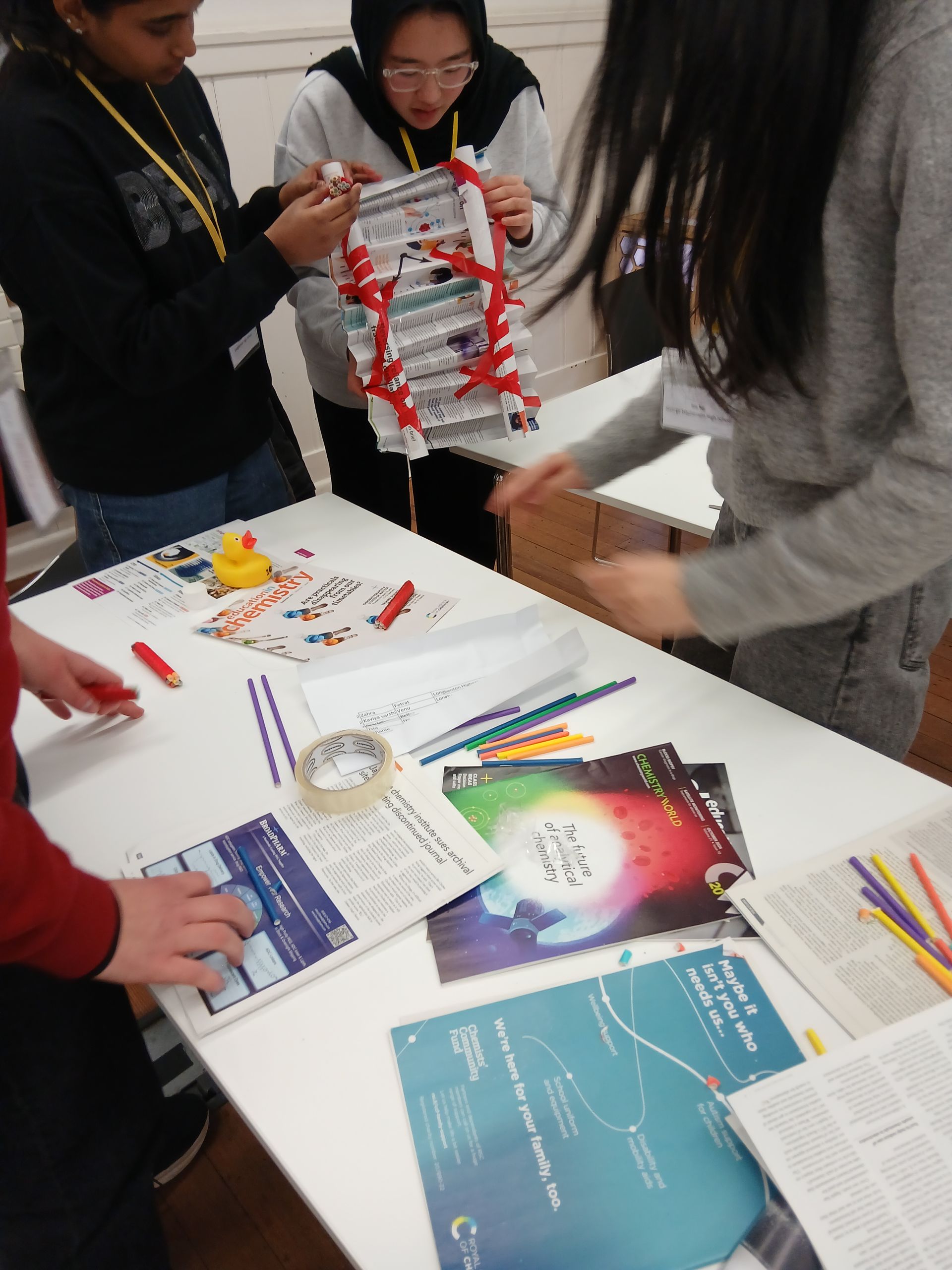 People gathered around a table with brochures, papers, and colorful markers during a group activity