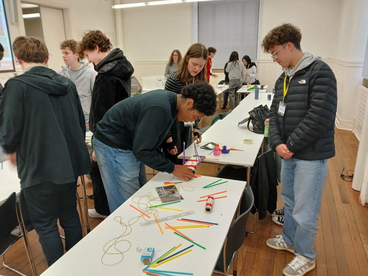 People gathered around tables in a bright room, creating colorful crafts and drawings on a workshop project.