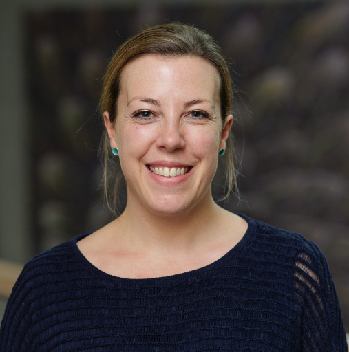 Smiling woman in a dark navy top against a blurred background