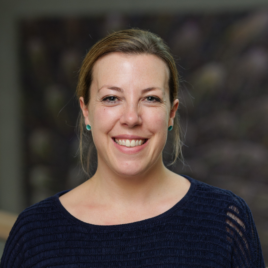Smiling woman in a dark sweater against a softly blurred background