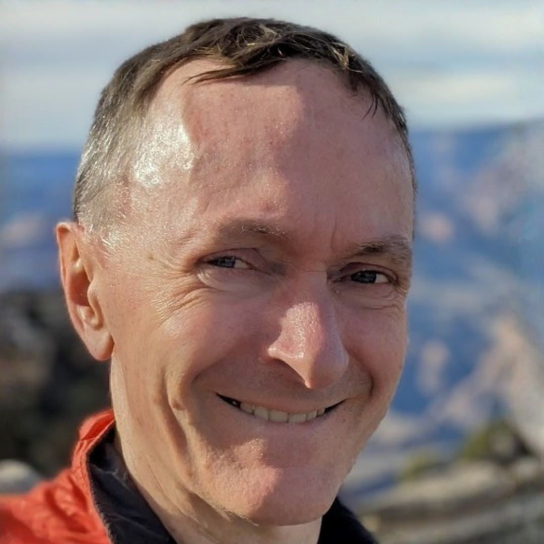 Smiling man outdoors with mountains blurred in the background
