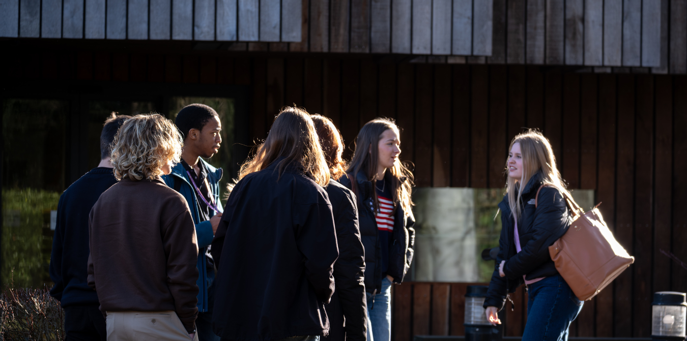 Group of people standing and talking outside a building in bright sunlight