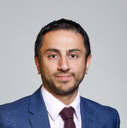 Head-and-shoulders portrait of a man in a blue suit and maroon tie against a gray background