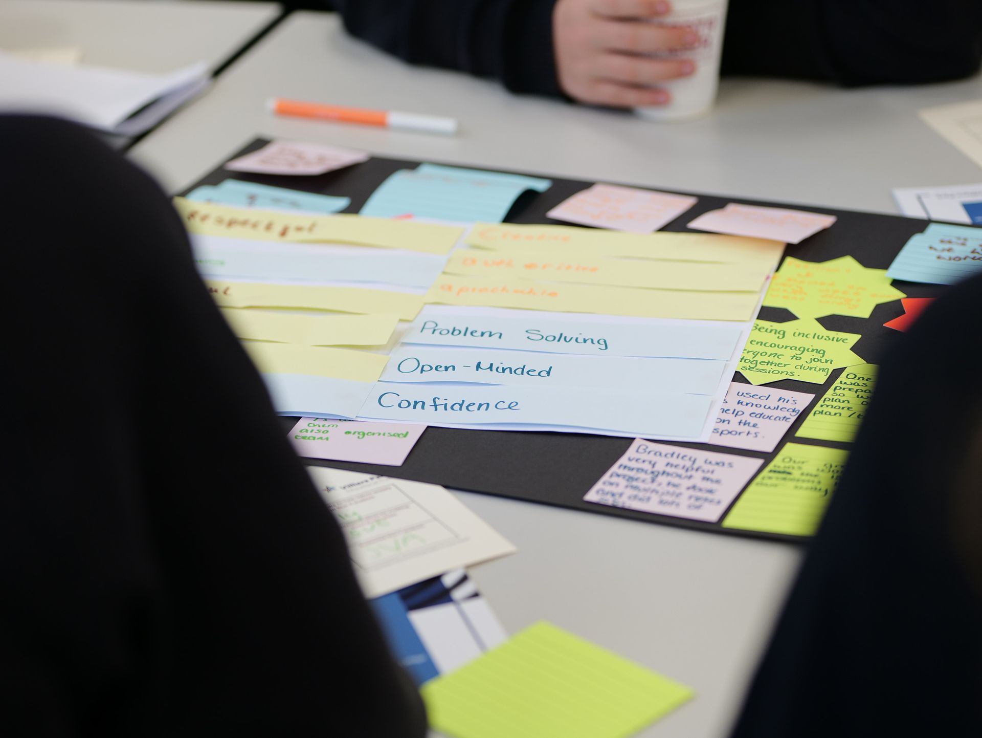 Hands sorting colorful notes and cards on a table during a planning meeting