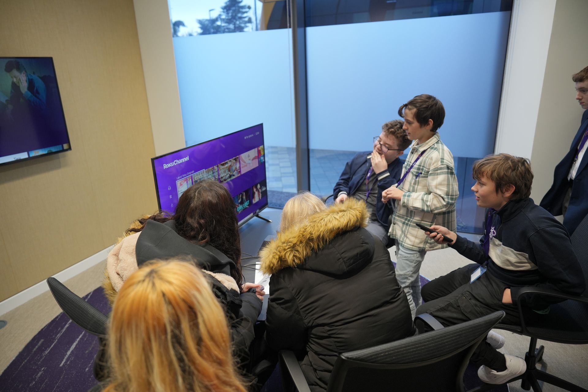 A group of people are sitting around a table in front of a television.