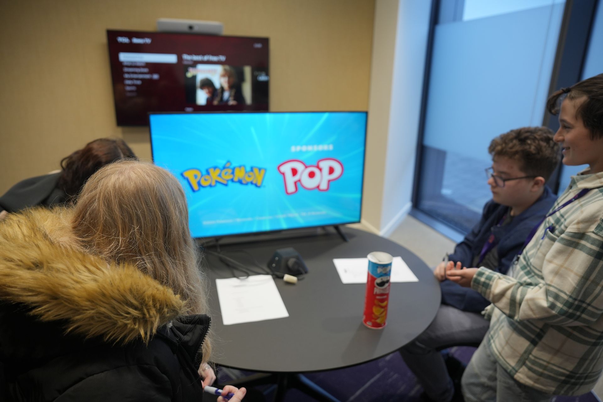 A group of people are sitting around a table playing pokemon pop.