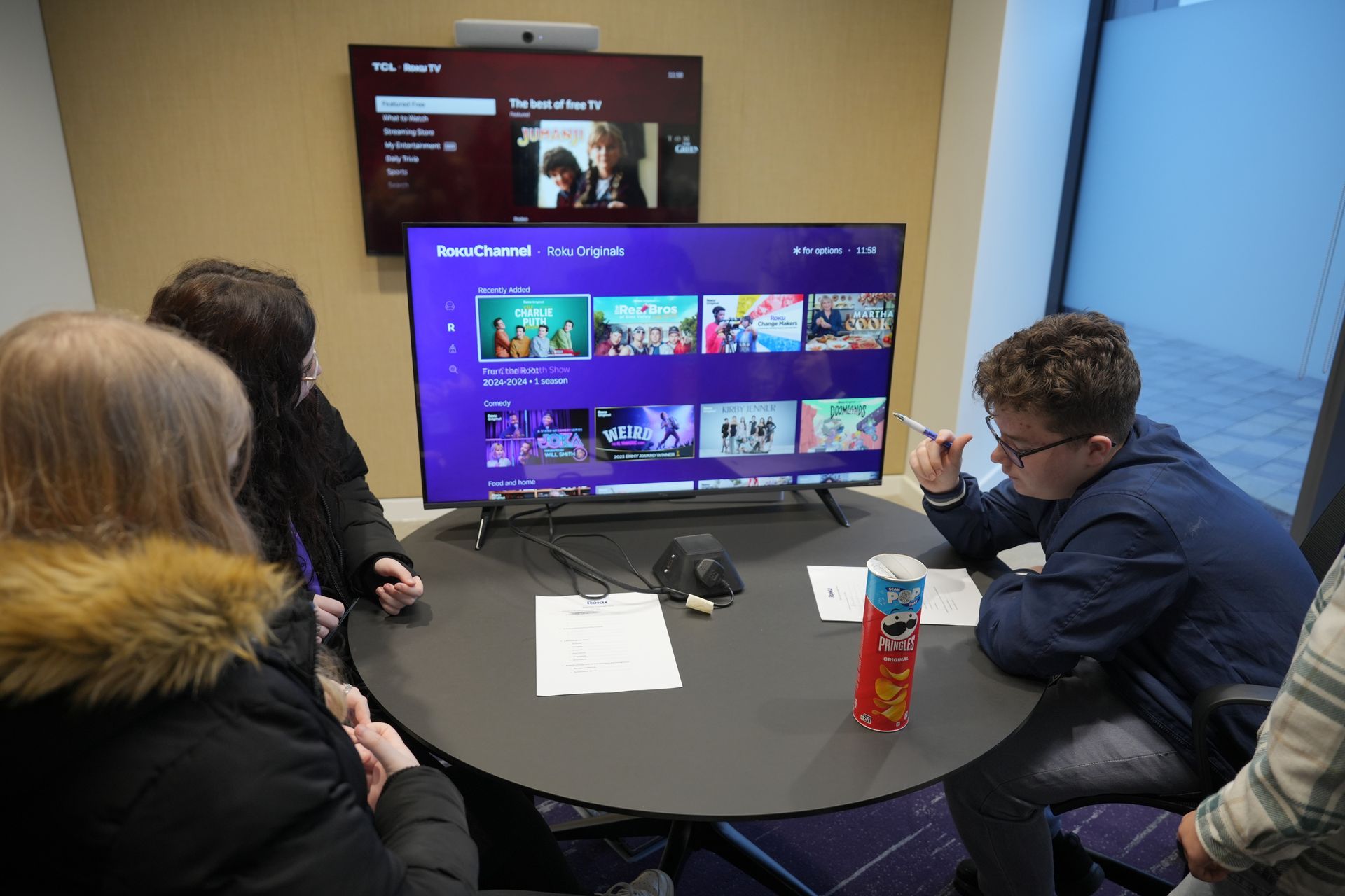 People seated around a table viewing a TV screen in a meeting room