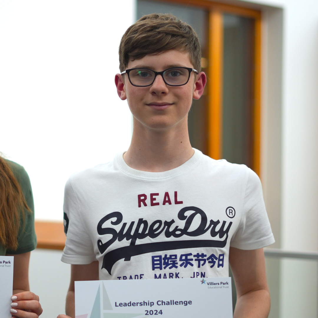 Teen in glasses holding a certificate indoors, wearing a white SuperDry T-shirt.