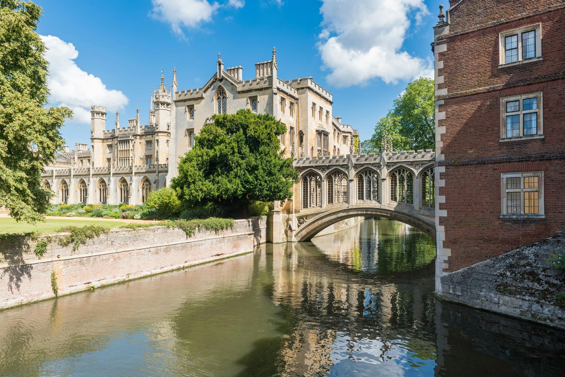 Historic stone bridge over a canal beside a cathedral-like building under a blue sky