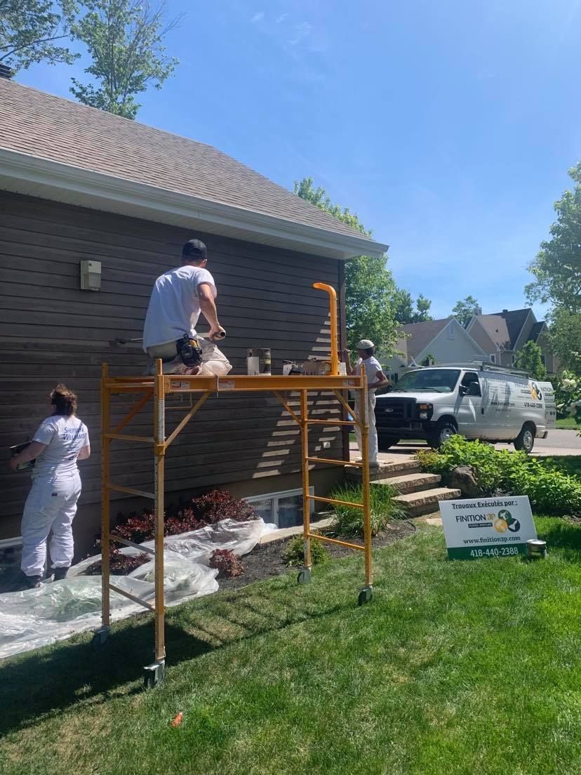 A group of people are painting a brick house.
