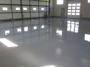 A large warehouse with a shiny concrete floor and a garage door.